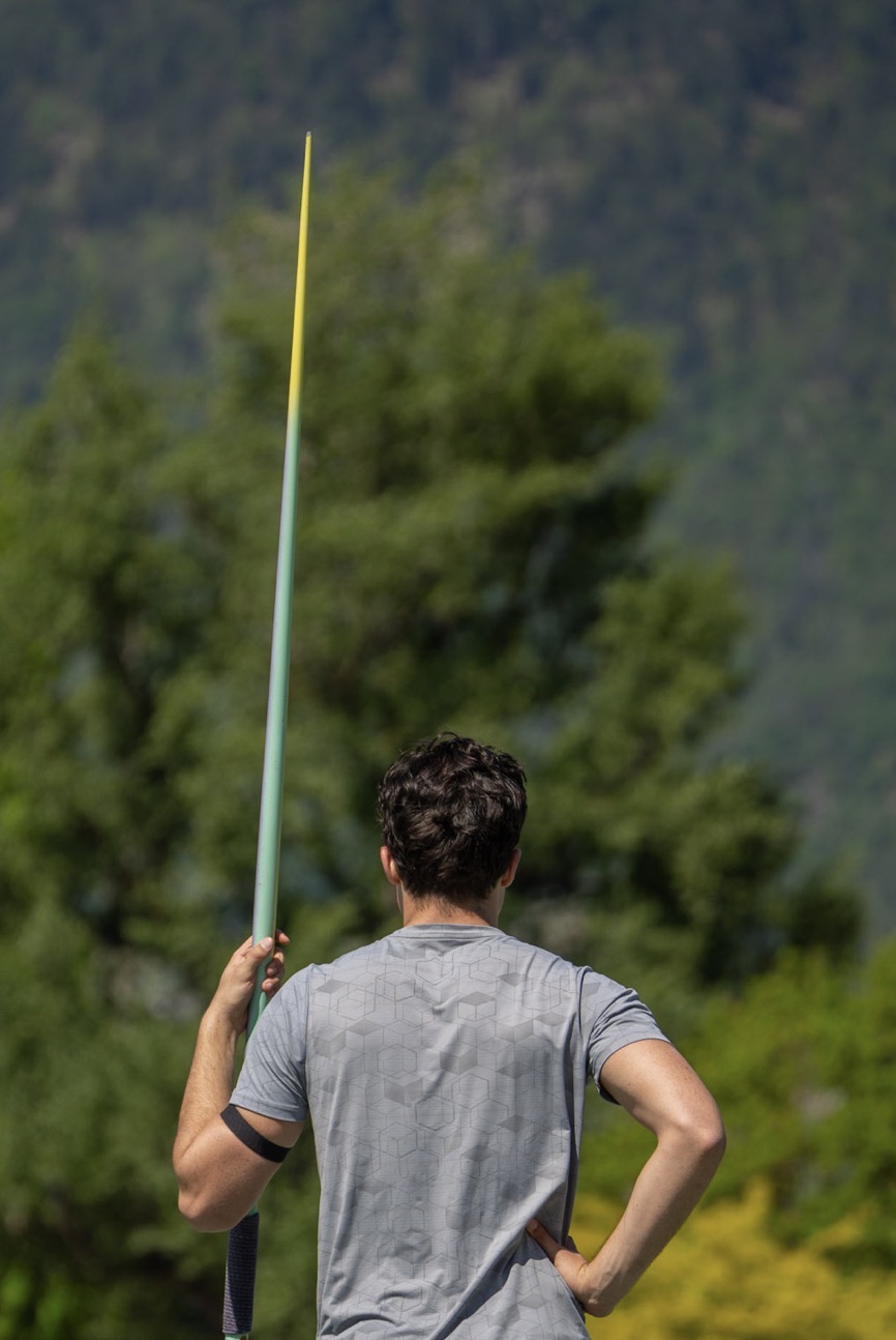 Cédric Blum with a javelin, mountains behind